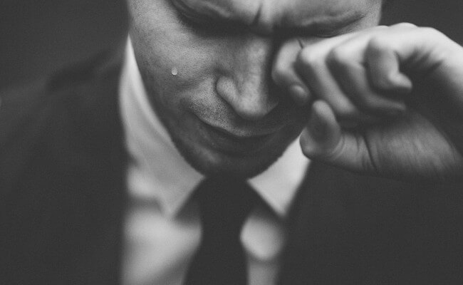 black-and-white shot of a crying man in a suit and tie