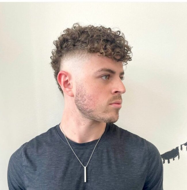 A rebellious look with a curly mohawk fade cut. 